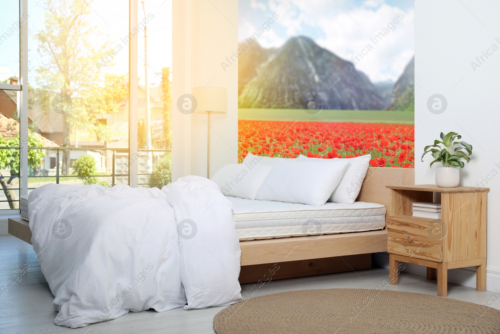 Image of Sunlit bedroom. Interior with comfortable bed and mountain landscape wallpapers