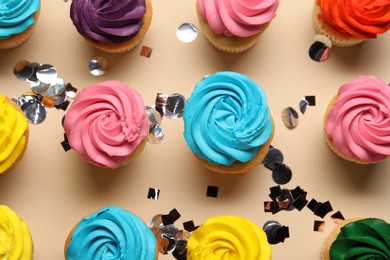 Photo of Delicious cupcakes with bright cream and confetti on beige background, flat lay