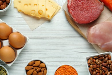 Different fresh products on white wooden table, flat lay with space for text. Sources of essential amino acids