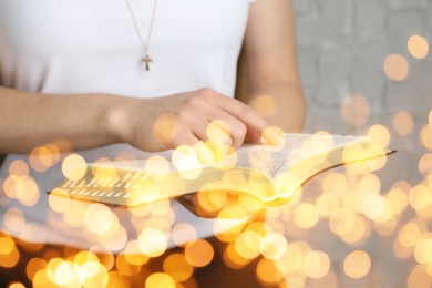 Image of Woman reading Bible near white wall, closeup. Bokeh effect