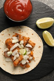 Photo of Delicious taco with vegetables, meat and ketchup on grey table, top view