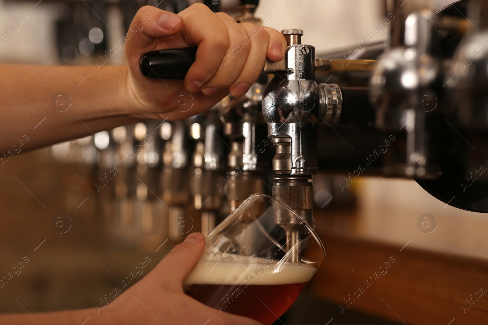 Photo of Bartender pouring fresh beer into glass in pub, closeup