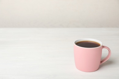 Pink ceramic cup with hot aromatic coffee on table