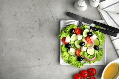Photo of Tasty fresh Greek salad on grey table, flat lay. Space for text