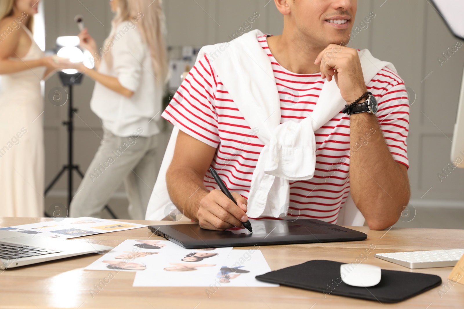 Photo of Professional retoucher working with graphic tablet at desk in photo studio, closeup