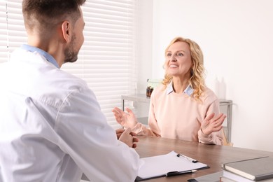 Photo of Doctor consulting patient at table in clinic