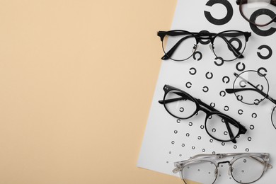 Photo of Vision test chart and glasses on beige background, flat lay. Space for text