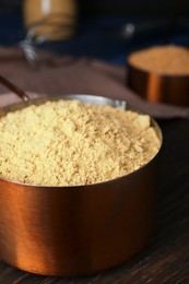 Photo of Saucepan with mustard powder on wooden table, closeup