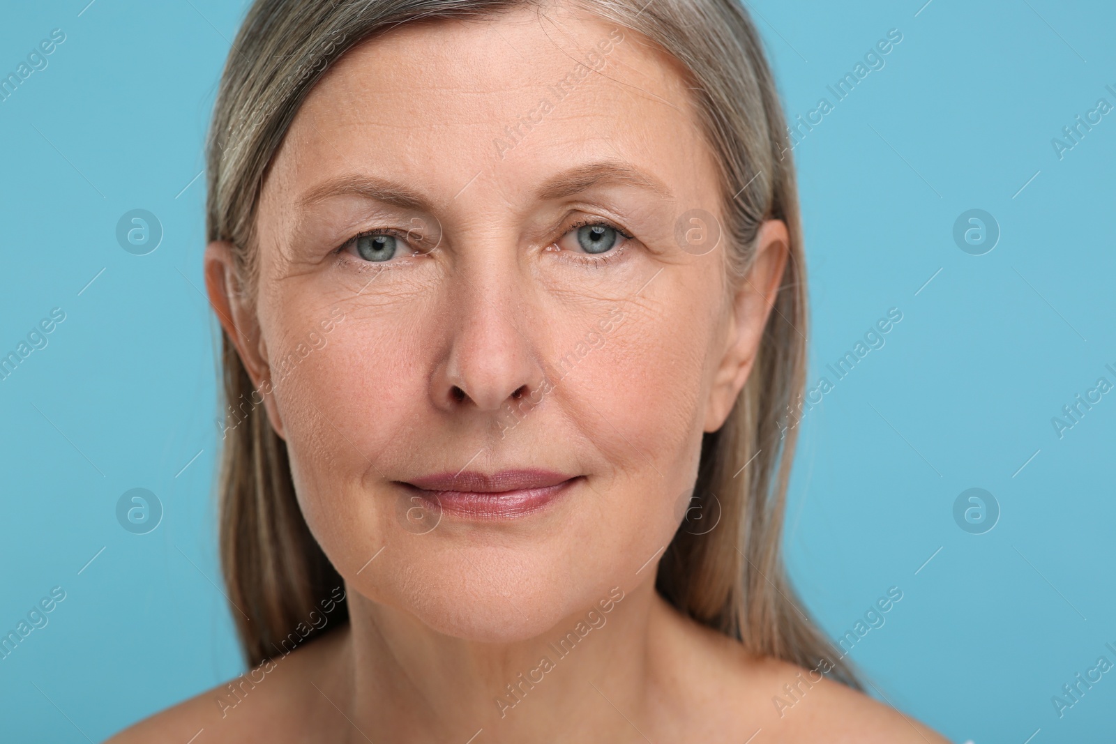 Photo of Portrait of senior woman with aging skin on light blue background. Rejuvenation treatment