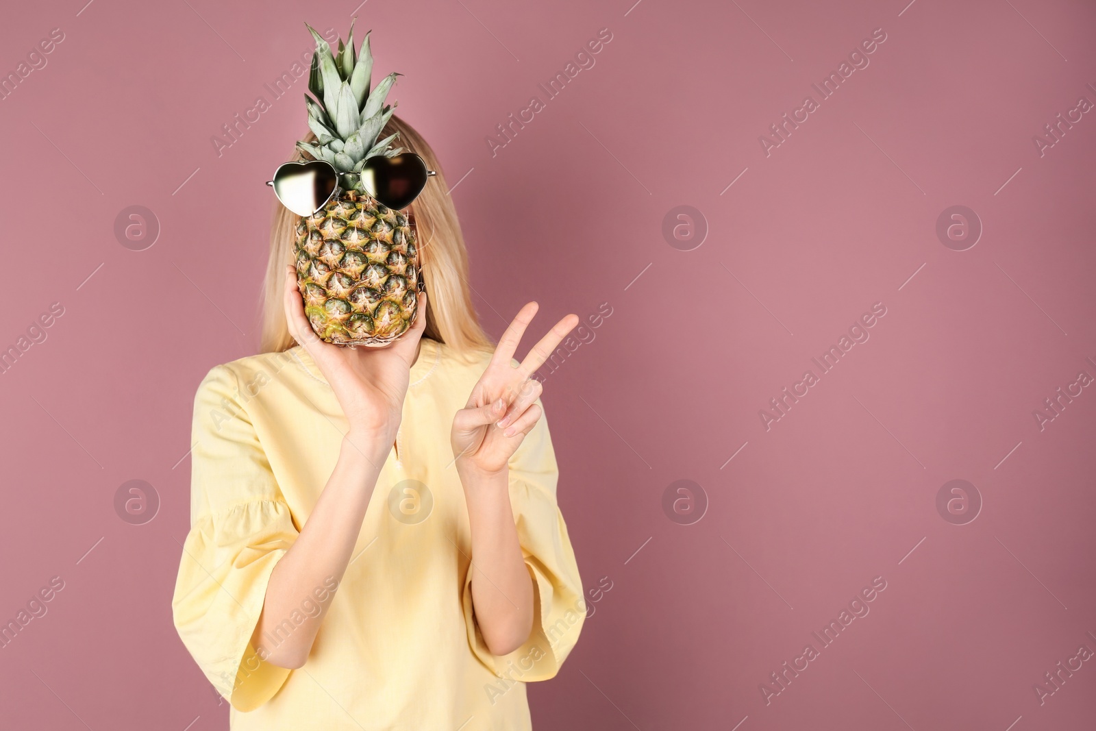 Photo of Woman holding pineapple with sunglasses on color background