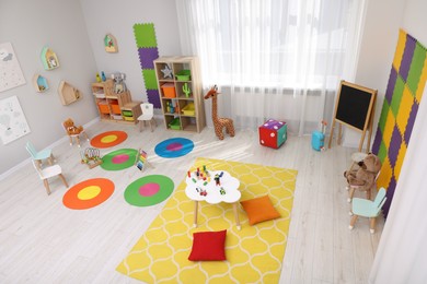 Child`s playroom with different toys and furniture, above view. Cozy kindergarten interior