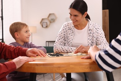 Photo of Family playing checkers at wooden table in room