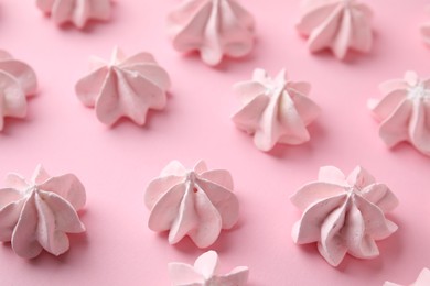 Many tasty meringue cookies on pink background, closeup