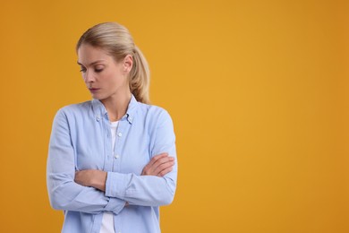 Photo of Resentful woman with crossed arms on orange background. Space for text