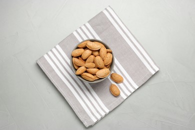 Photo of Ceramic bowl with almonds on grey table, top view. Cooking utensil