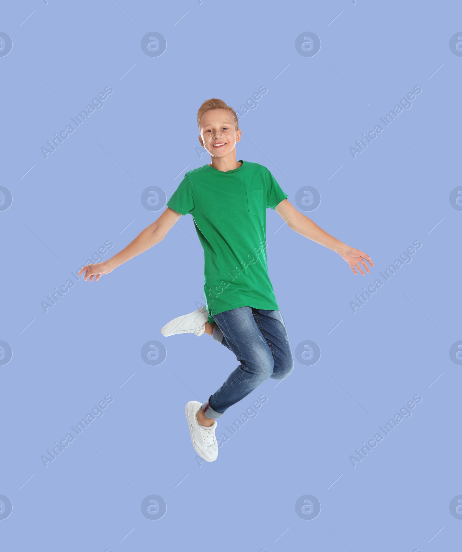 Image of Teenage boy jumping on light blue background, full length portrait