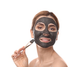 Photo of Beautiful woman applying black mask onto face against white background