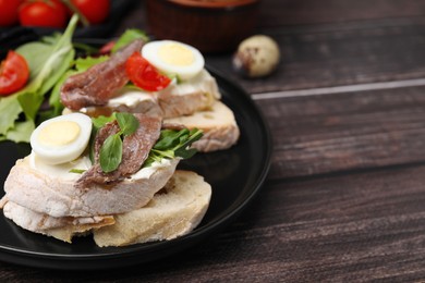 Delicious bruschettas with anchovies, cream cheese, arugula, eggs and tomatoes on wooden table, closeup. Space for text