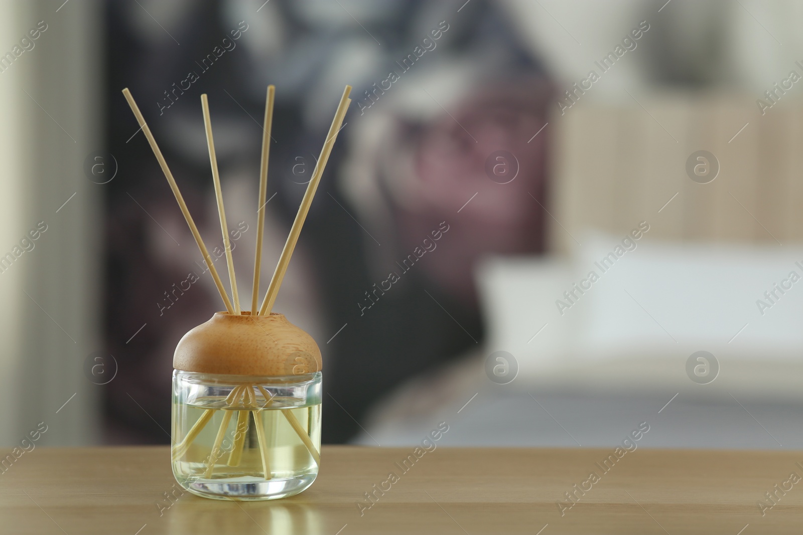 Photo of Aromatic reed air freshener on table indoors. Space for text