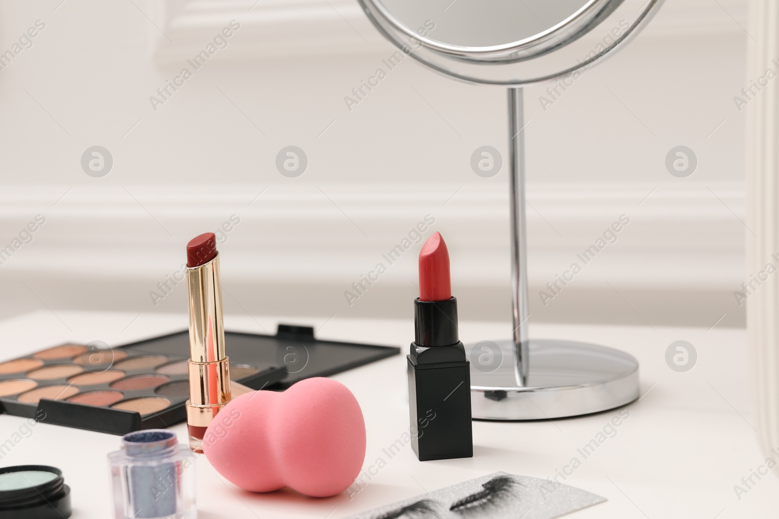 Photo of Mirror and cosmetic products on white dressing table, closeup