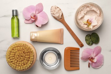 Flat lay composition with different spa products and flowers on white marble table