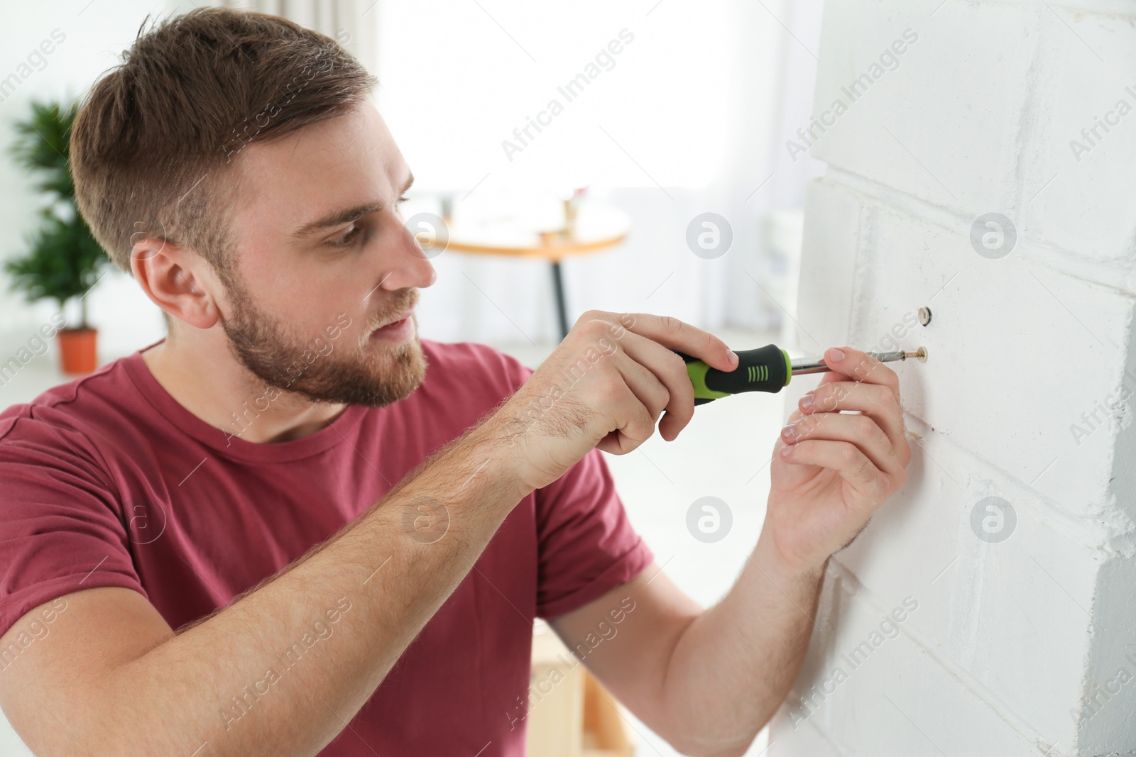 Photo of Young working man using screwdriver at home