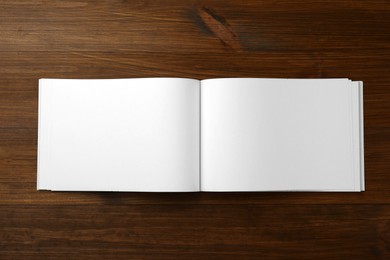 Photo of Open blank paper brochure on wooden table, top view. Mockup for design