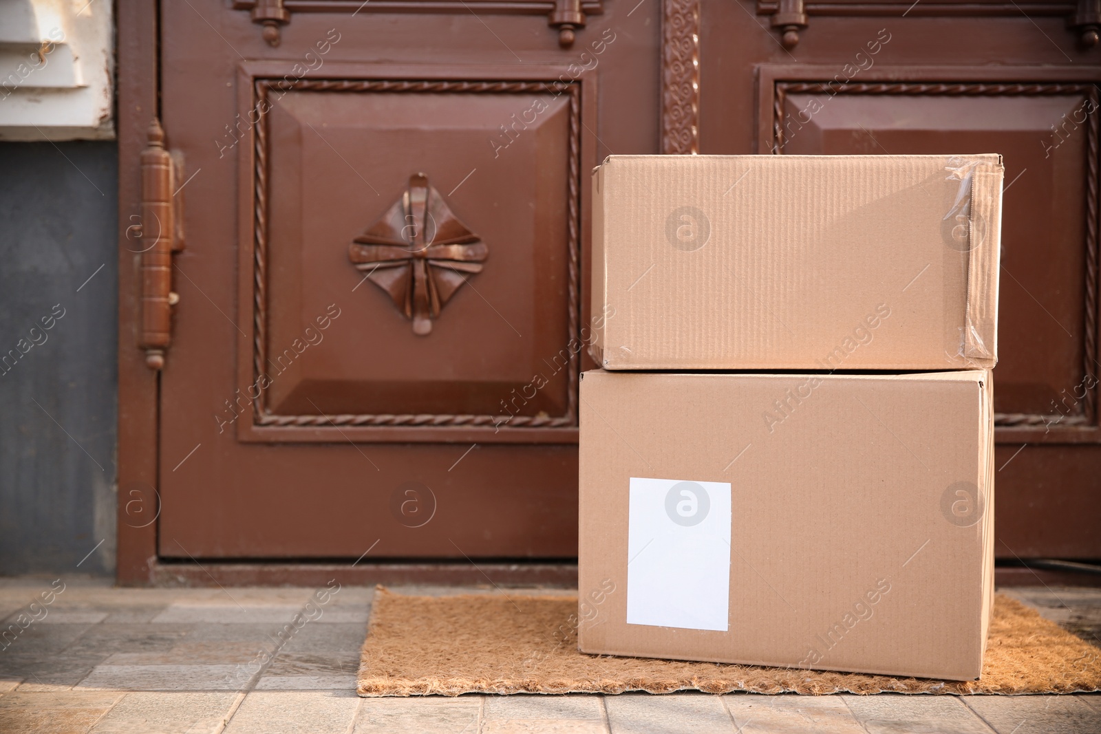 Photo of Delivered parcels on door mat near entrance. Space for text