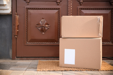 Photo of Delivered parcels on door mat near entrance. Space for text