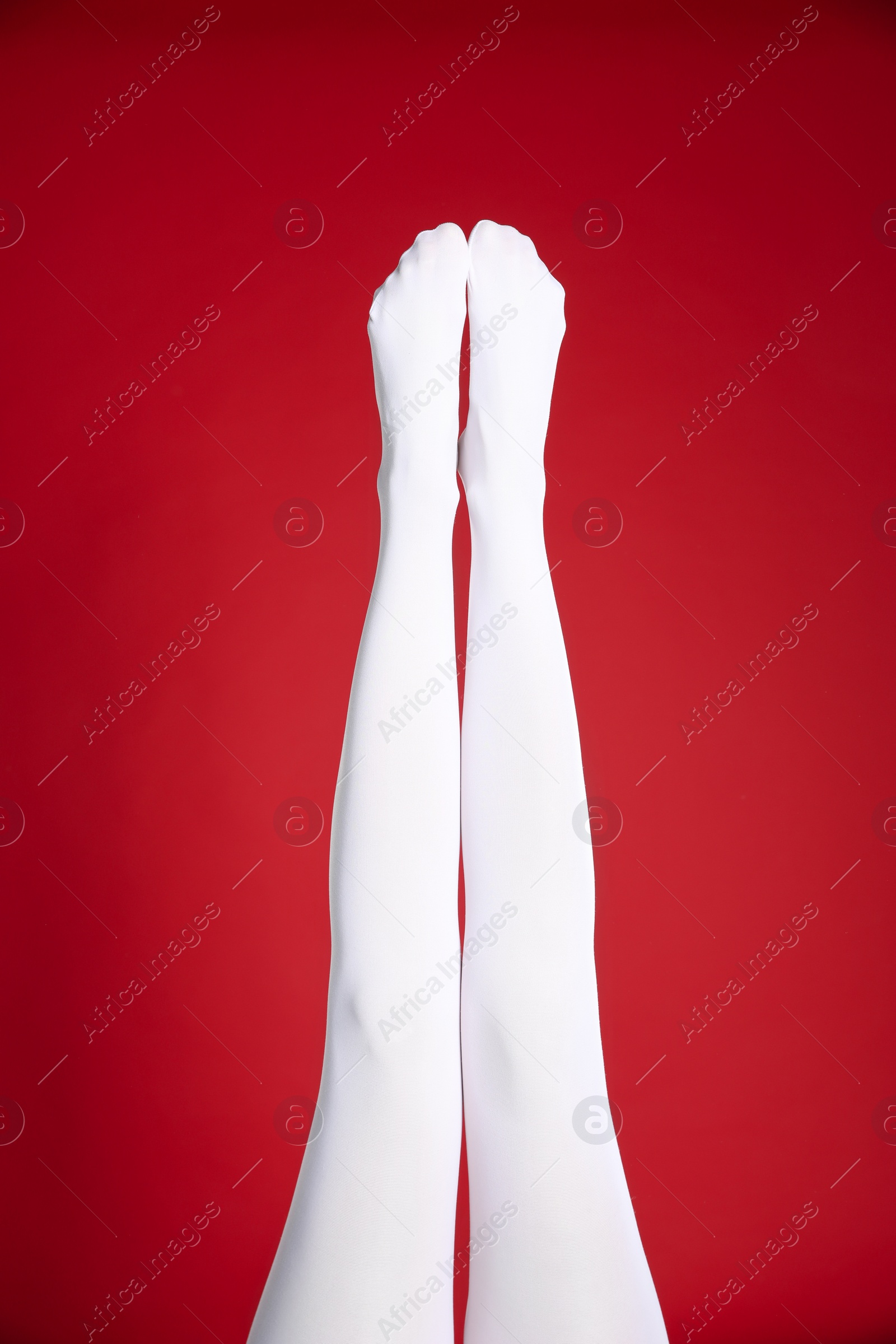 Photo of Woman wearing white tights on red background, closeup of legs