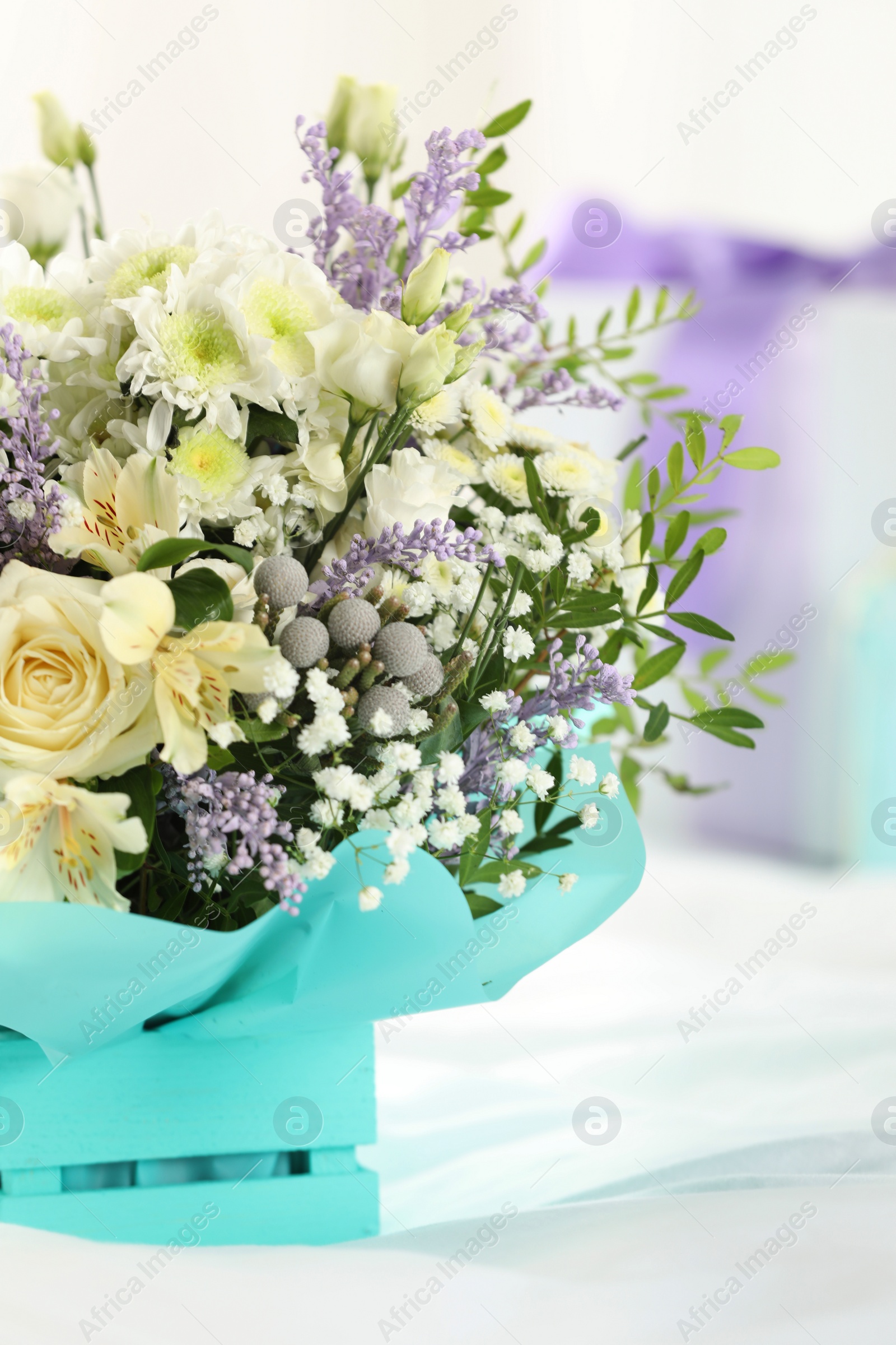 Photo of Beautiful bouquet of flowers in decorative crate on bed, closeup