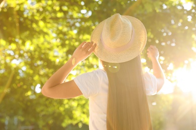 Young woman in hat outdoors on sunny day, back view