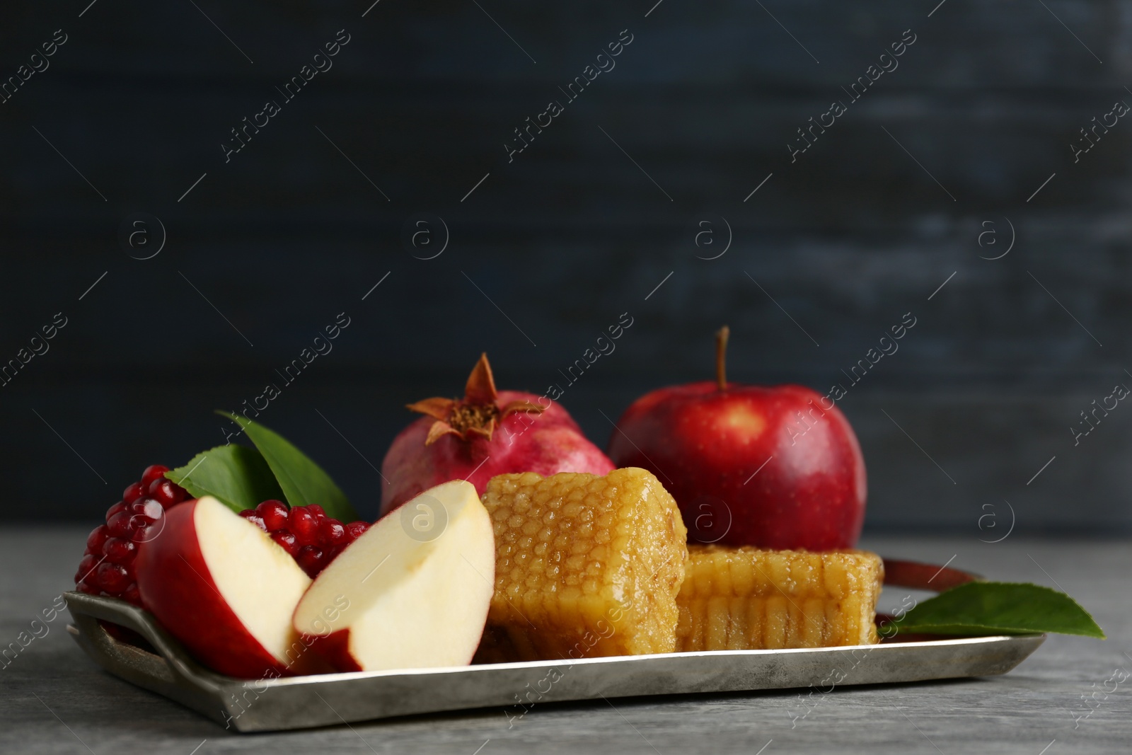 Photo of Honeycombs, apples and pomegranate on grey table. Rosh Hashanah holiday