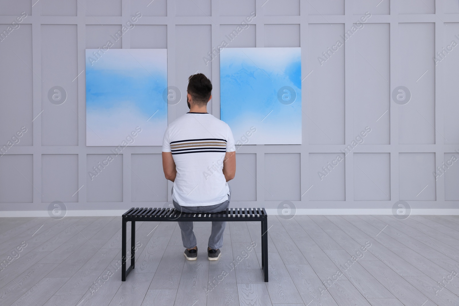 Photo of Man at exhibition in art gallery, back view