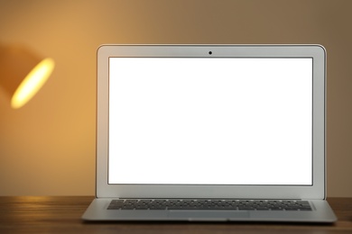 Photo of Laptop with blank screen on table indoors. Space for text