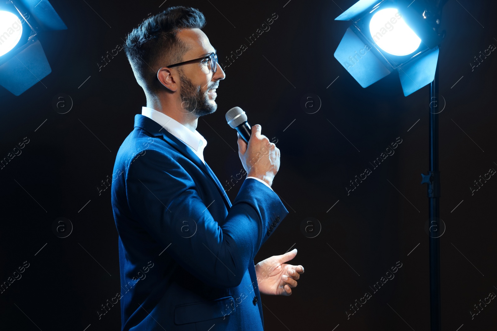 Photo of Motivational speaker with microphone performing on stage. Space for text