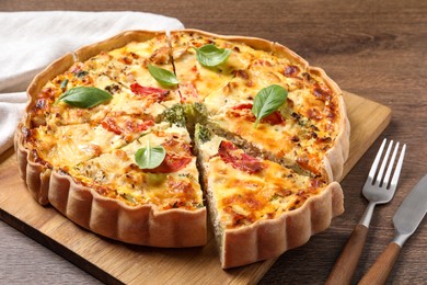Photo of Tasty quiche with tomatoes, basil and cheese on wooden table, closeup