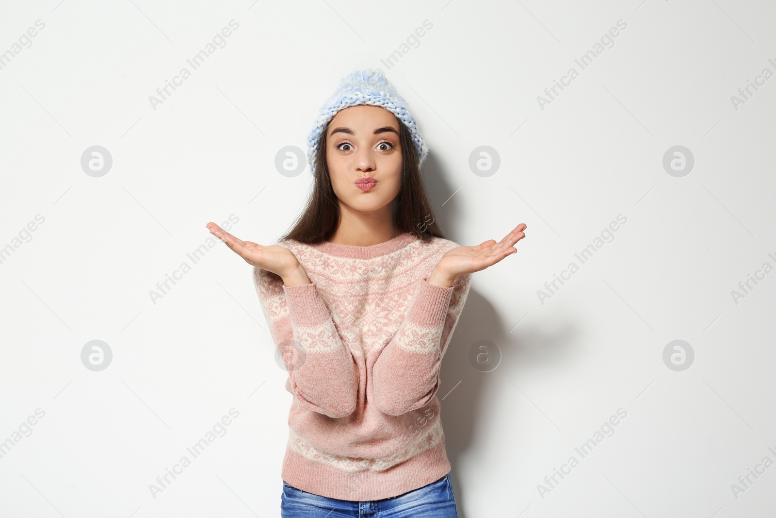 Photo of Young woman in warm sweater and knitted hat on white background. Celebrating Christmas