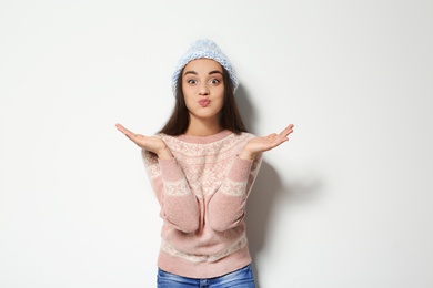 Photo of Young woman in warm sweater and knitted hat on white background. Celebrating Christmas