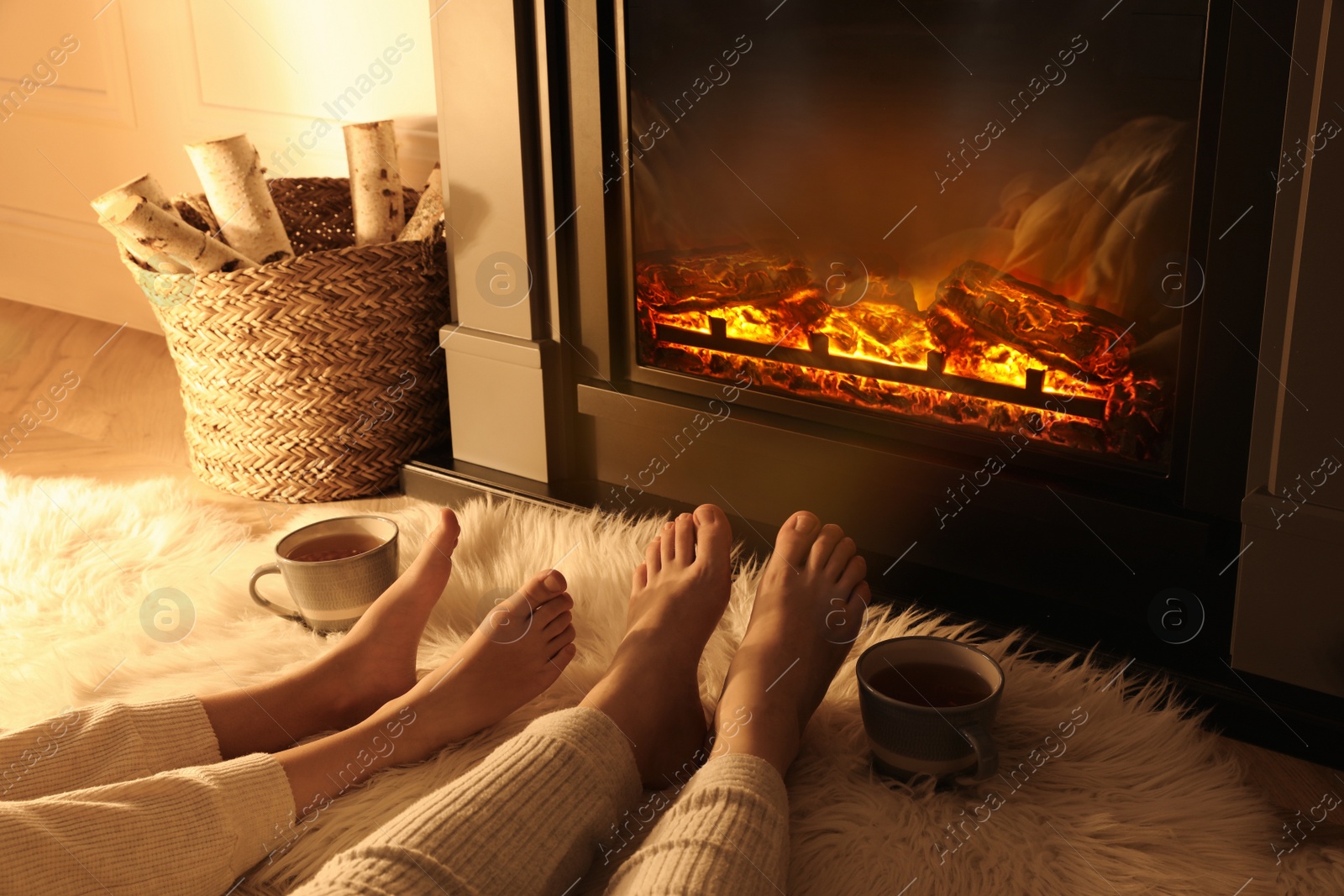 Photo of Couple resting near fireplace at home, closeup of legs