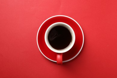 Photo of Aromatic coffee in cup on red background, top view