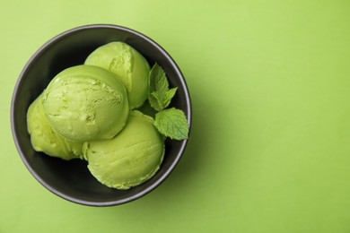 Photo of Tasty matcha ice cream in bowl on green table, top view. Space for text