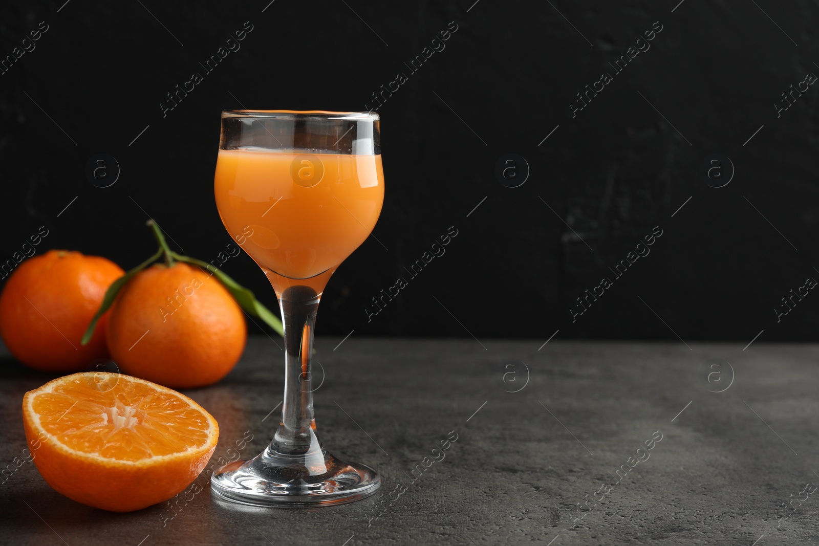 Photo of Delicious tangerine liqueur and fresh fruits on grey table, space for text