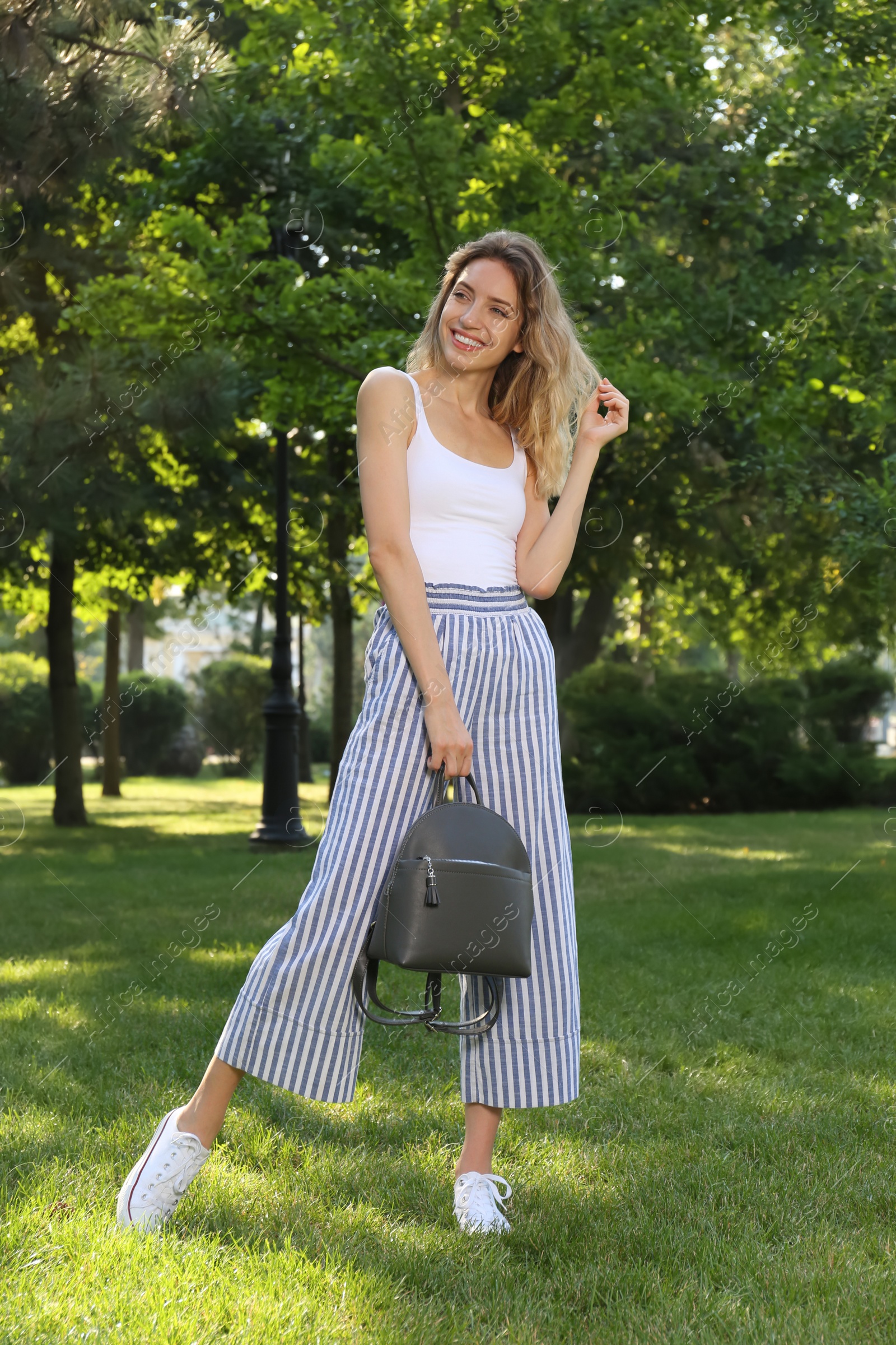 Photo of Young woman with stylish backpack in park