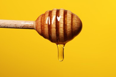 Photo of Pouring honey from dipper against golden background, closeup. Space for text