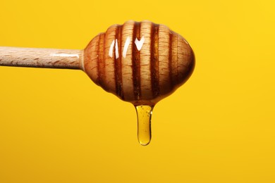 Pouring honey from dipper against golden background, closeup. Space for text