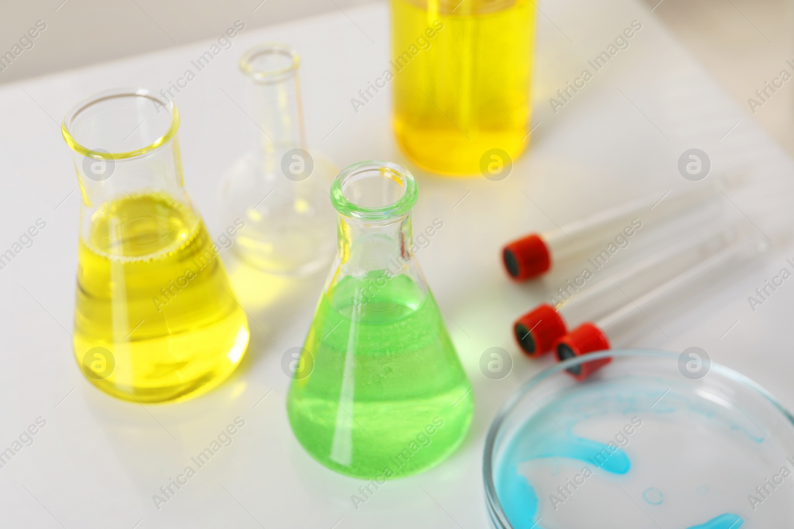 Photo of Laboratory analysis. Different glassware with liquids on white table