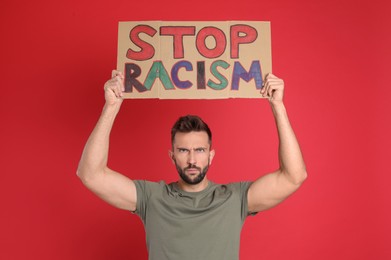 Man holding sign with phrase Stop Racism on red background