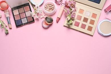 Photo of Flat lay composition with eyeshadow palettes and beautiful flowers on pink background, space for text