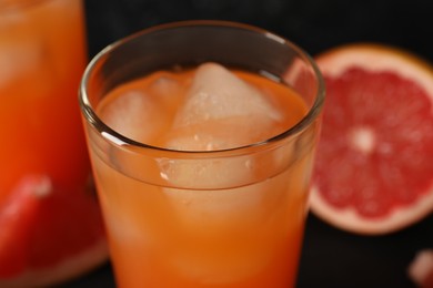 Photo of Tasty grapefruit drink with ice in glass on blurred background, closeup